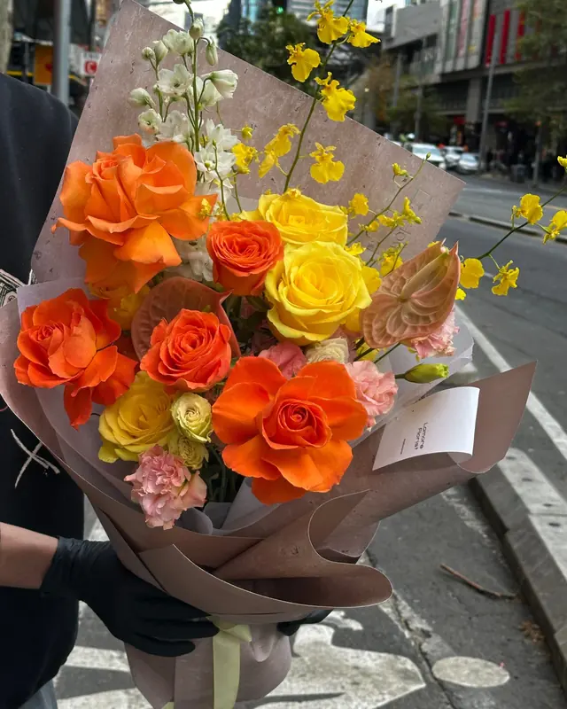 Bright Horizon: orange and yellow roses with oncidium in brown wrap